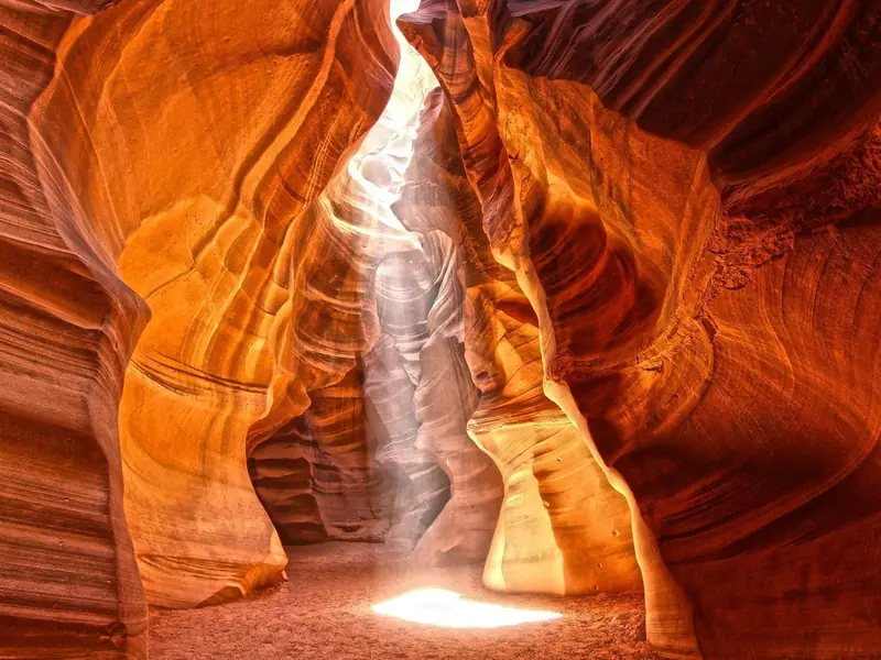 Vertical light beams striking the floor of Upper Antelope Canyon at midday